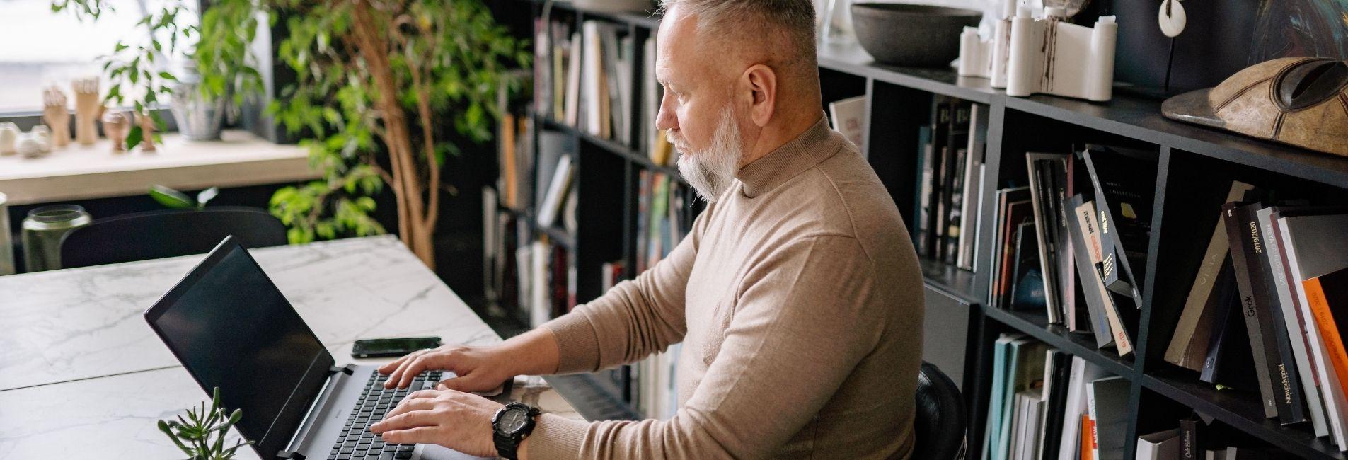 Man sitting at desk in home office with laptop