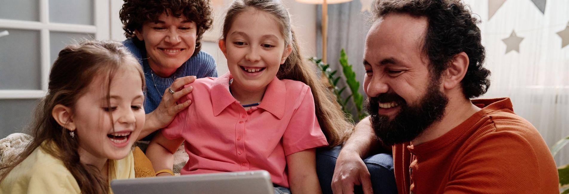 Family outside on laptop smiling together